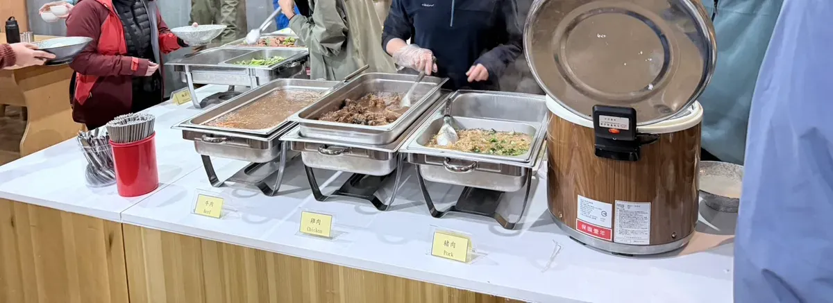 排雲山莊取餐檯，三個保溫餐盤分別標示牛肉、雞肉、豬肉，旁邊是保溫飯桶