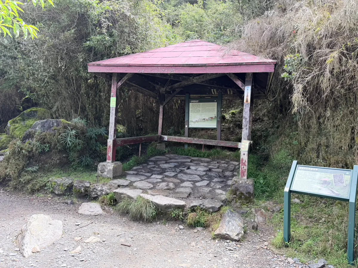 玉山步道上的孟祿亭,紅色屋頂的木造涼亭與石板地面,旁邊立著解說牌