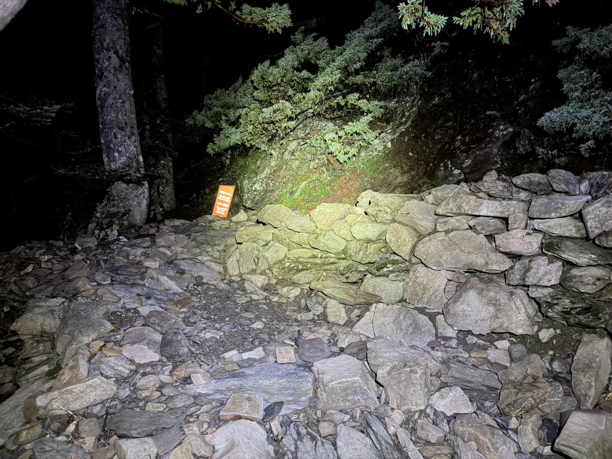 凌晨摸黑出發的玉山步道,頭燈照亮滿是碎石的路面與石砌駁坎,四周一片漆黑