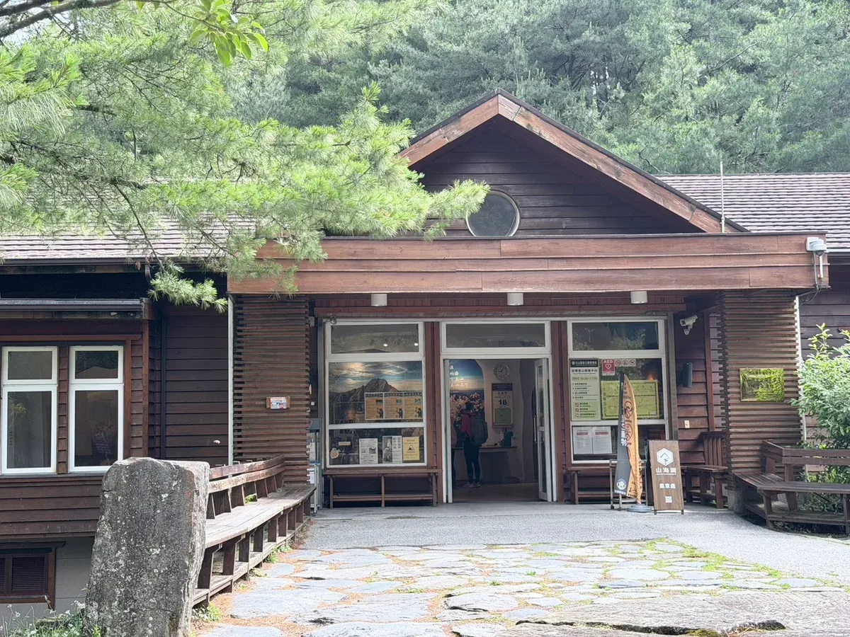 排雲登山服務中心的木造外觀,門口掛著開放時間 06:30 到 17:00 的告示牌