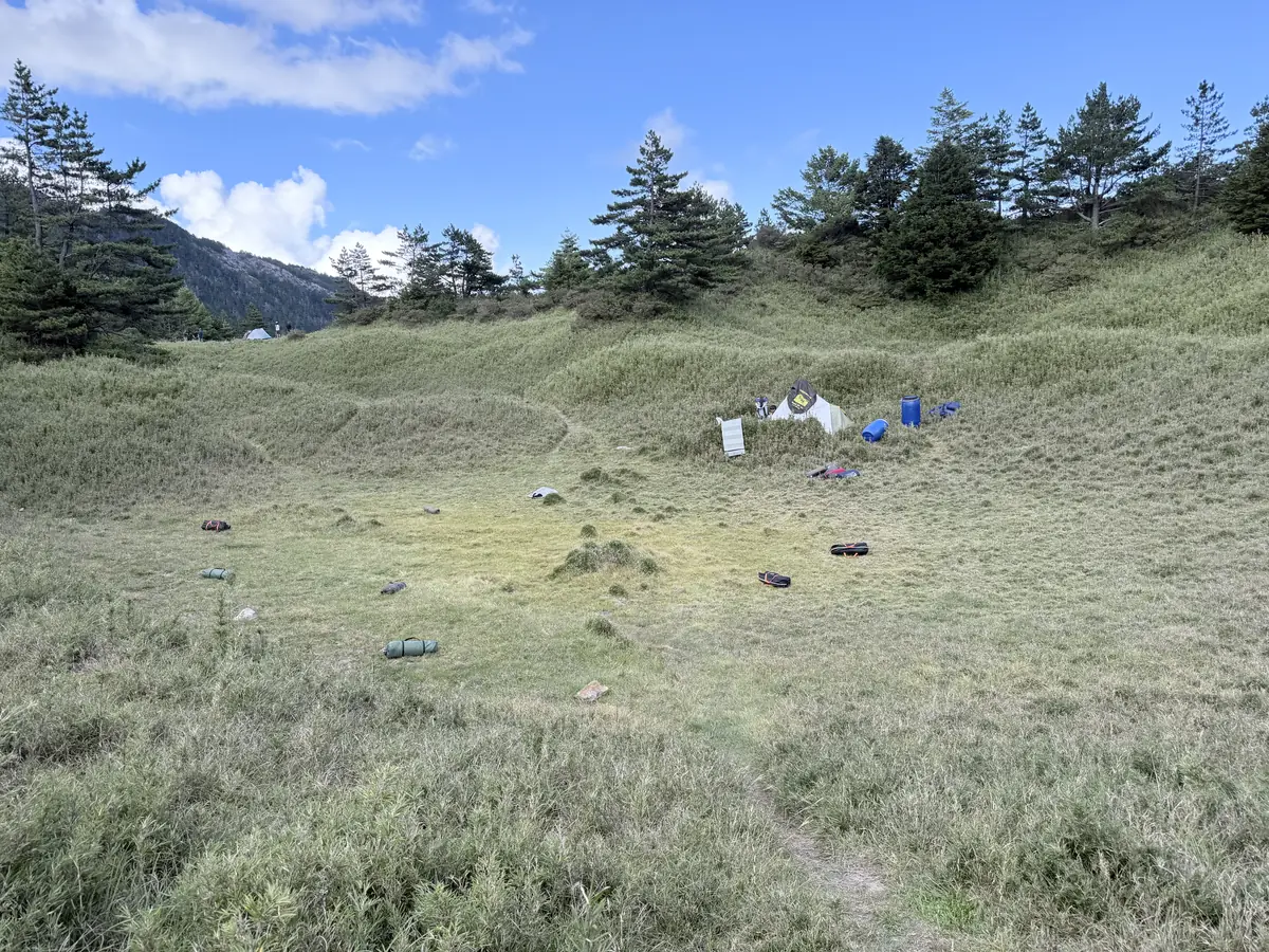 小完美谷的高山草原，藍天白雲下遠處搭著幾頂帳篷
