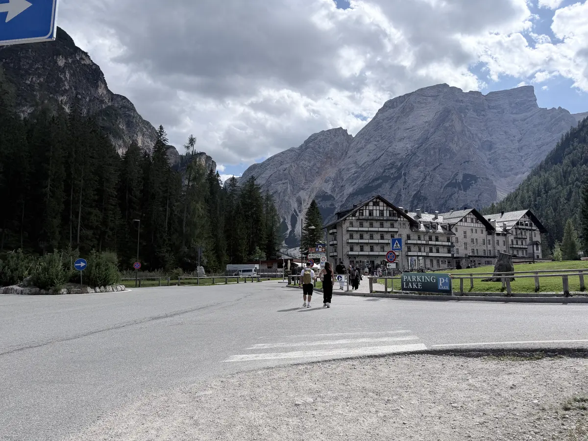 從停車場往湖邊走的柏油路，前方是 Hotel Lago di Braies 的建築與後方山峰