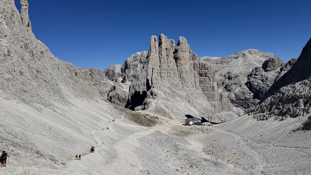 下山途中回望 Gartl 盆地，Vajolet 三塔下方是 Gartlhütte 山屋，碎石路上有零星健行者