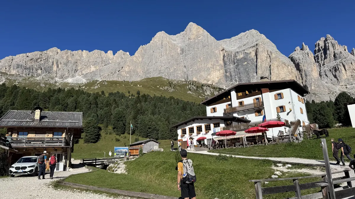 Rifugio Gardeccia 山屋與戶外紅色遮陽傘，旁邊是木屋，後方是陽光下的岩壁