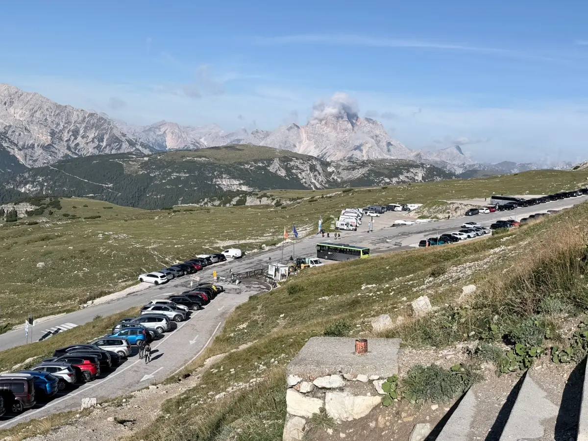Auronzo 停車場沿著山坡分層排滿車輛，遠方是多洛米蒂的連綿山脈