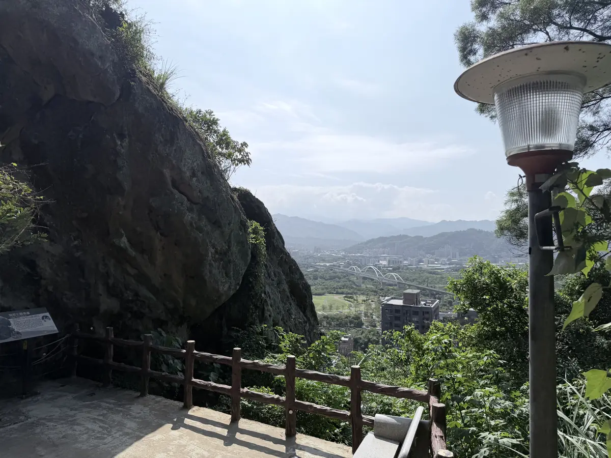 鶯歌石觀景台，左邊是鶯歌石的深色巨岩，欄杆外是鶯歌市區和遠方的山