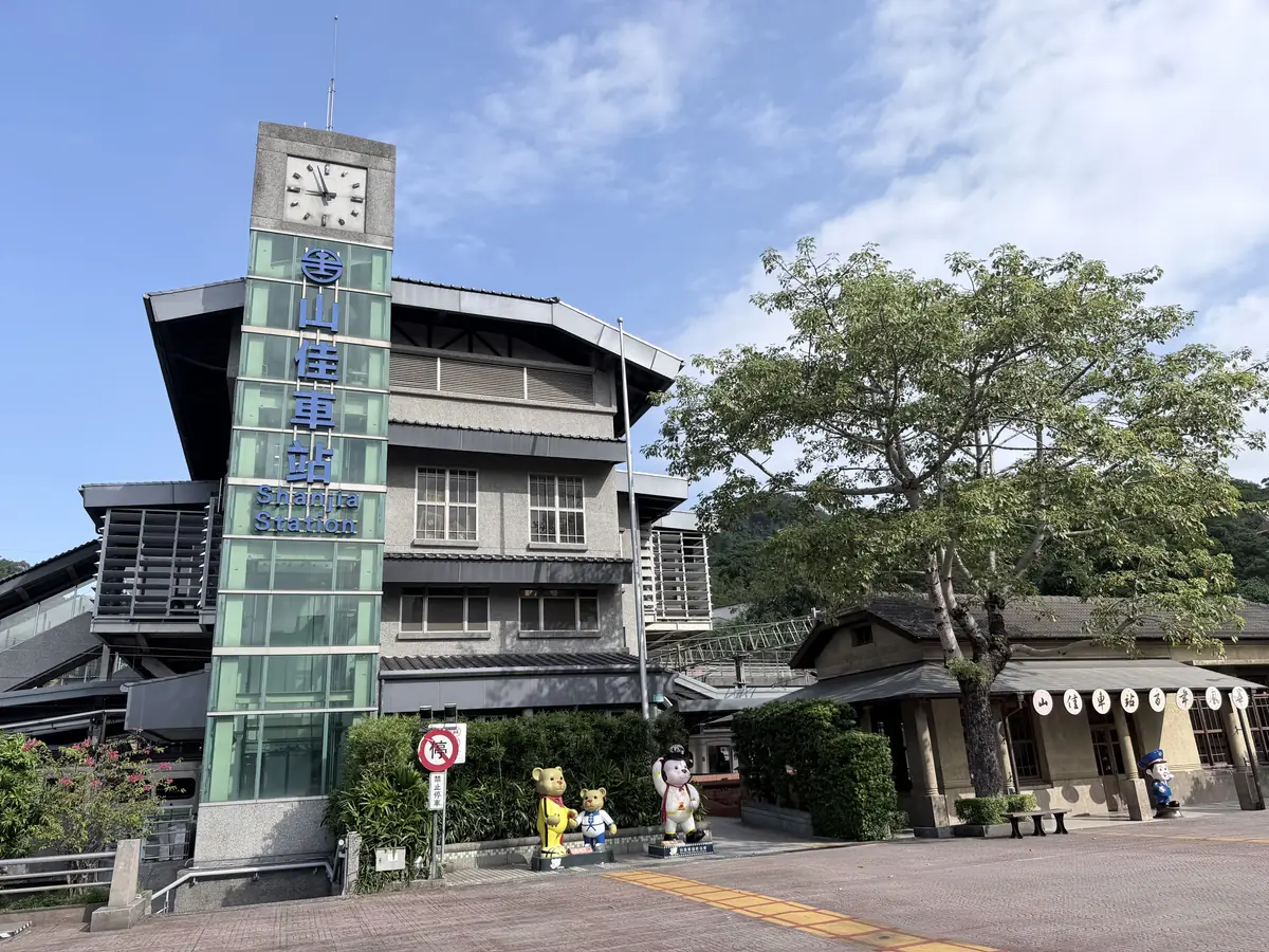 台鐵山佳車站，綠色鐘塔和旁邊的舊站房，站前有一棵大樹
