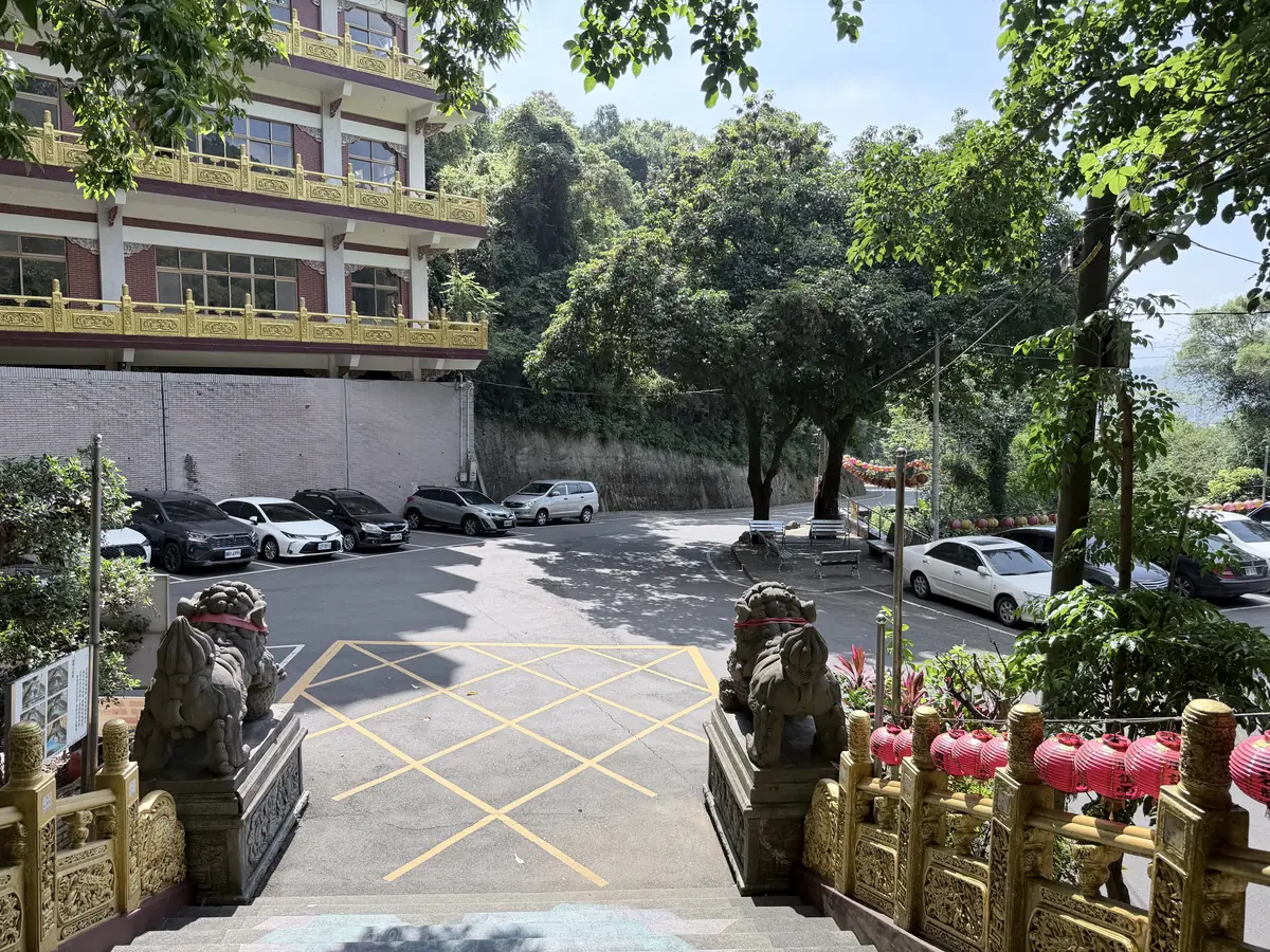 碧龍宮旁的停車場，停著幾台汽車，前面是廟門口的石獅