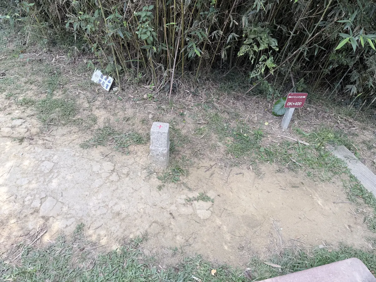 牛灶坑山的三角點石柱，頂端畫著紅色十字，旁邊插著牛灶山步道 0K+400 的里程牌